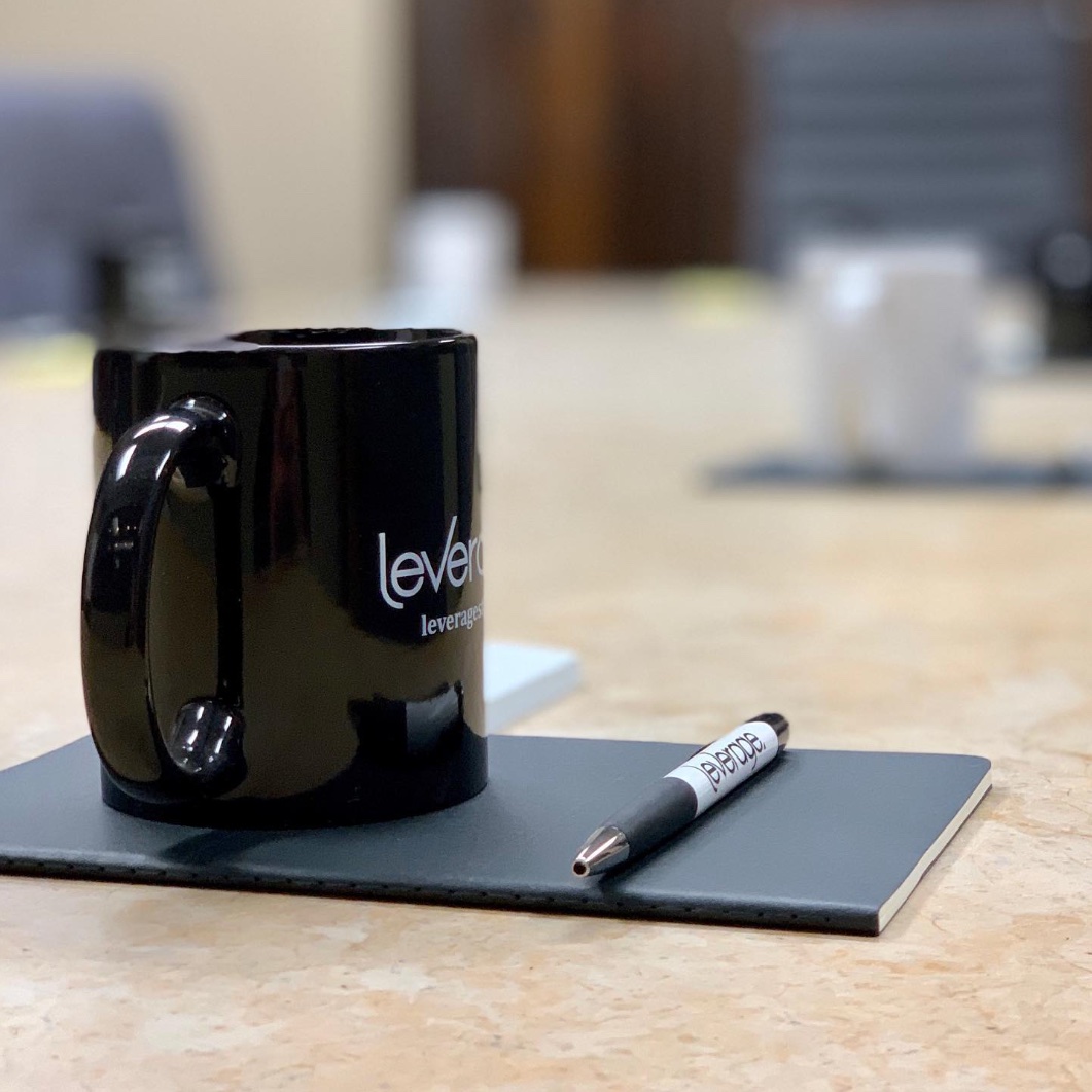Leverage branded mug sitting on top of notebook