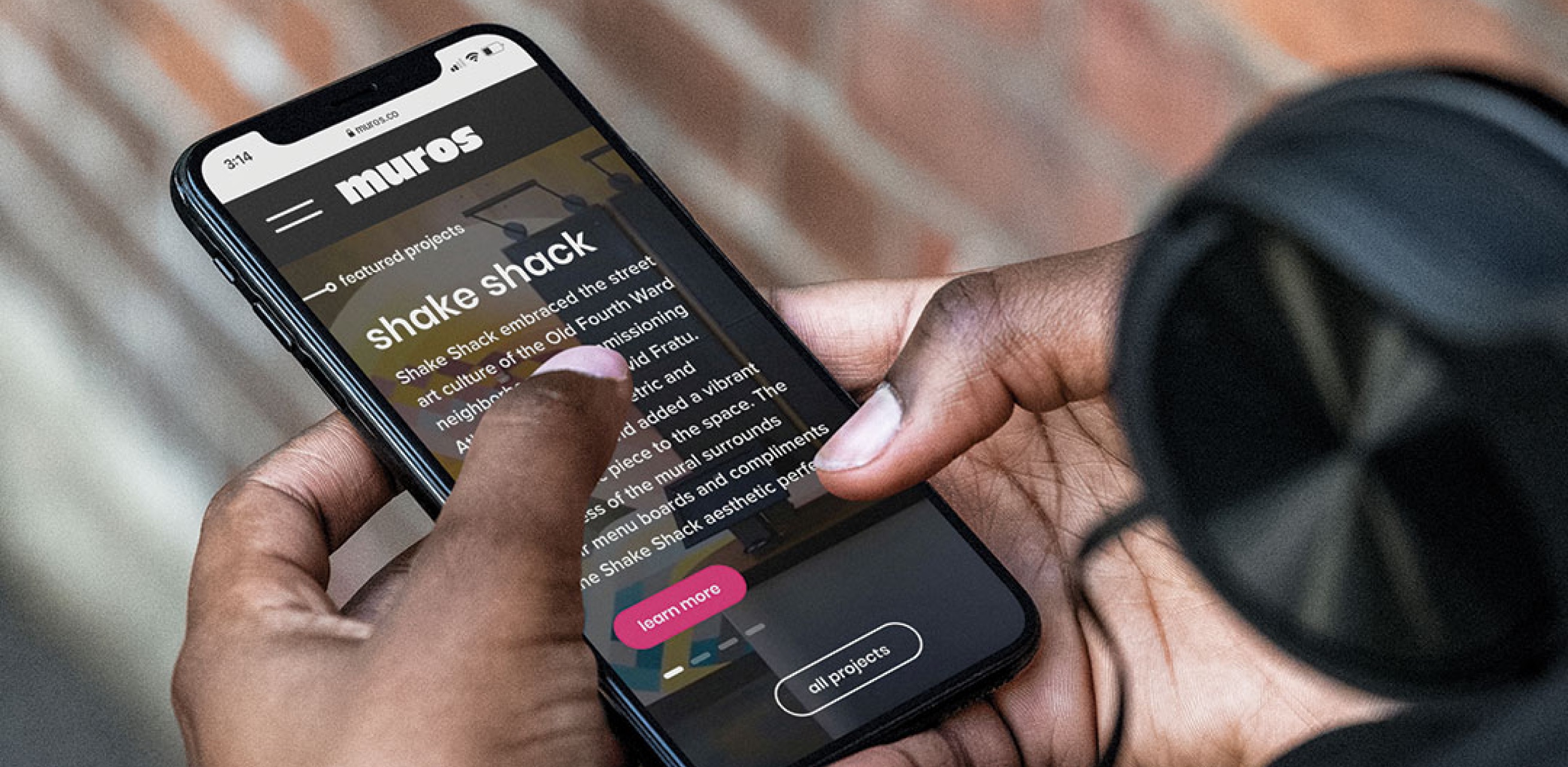 Holding a phone showing the muros.com website